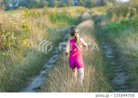 Little girl running on a field road Little girl running on a field road 135844708