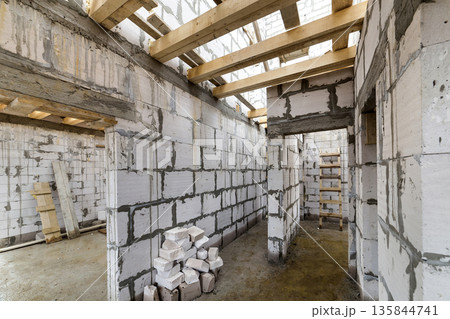 House room interior under construction and renovation. Energy saving walls of hollow foam insulation blocks, wooden ceiling beams and roof frame. House room interior under construction and renovation. Energy saving walls of hollow foam insulation blocks, wooden ceiling beams and roof frame. 135844741