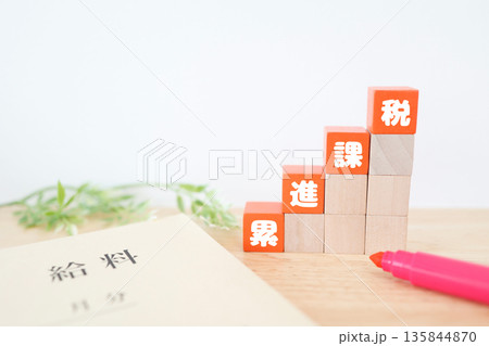 累進課税を示す給料袋と階段状ブロック。 135844870