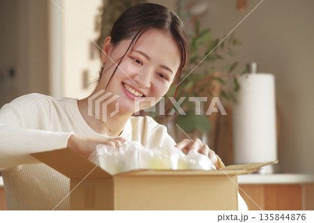荷物を開封して嬉しそうな日本人女性 135844876