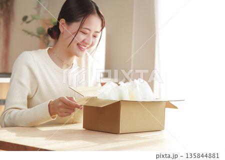 荷物を開封して嬉しそうな日本人女性 荷物を開封して嬉しそうな日本人女性 135844881