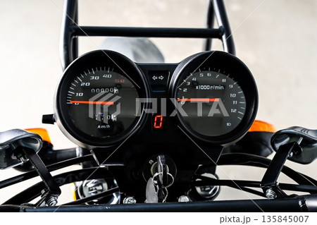 Motorcycle instrument panel close up showing speedometer tachometer and neutral indicator with ignition key. Modern bike dashboard detail. Motorcycle instrument panel close up showing speedometer tachometer and neutral indicator with ignition key. Modern bike dashboard detail. 135845007