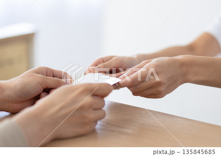 受付でカードを受け取る白衣姿の女性 受付でカードを受け取る白衣姿の女性 135845685
