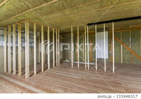 Construction and renovation of big spacious empty unfinished attic room with oak floor, walls and ceiling insulated with rock wool and fiber glass for cold barrier and wooden frame for future walls. 135846317