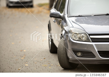 Gray shiny car parked in quiet area on asphalt road on blurred bokeh background on bright sunny day. Transportation and parking concept. Gray shiny car parked in quiet area on asphalt road on blurred bokeh background on bright sunny day. Transportation and parking concept. 135846387