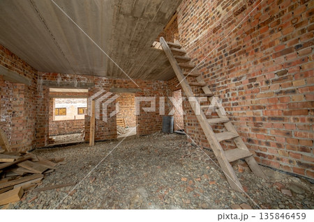 Interior of unfinished brick house with concrete floor and bare walls ready for plastering under construction. Real estate development Interior of unfinished brick house with concrete floor and bare walls ready for plastering under construction. Real estate development 135846459