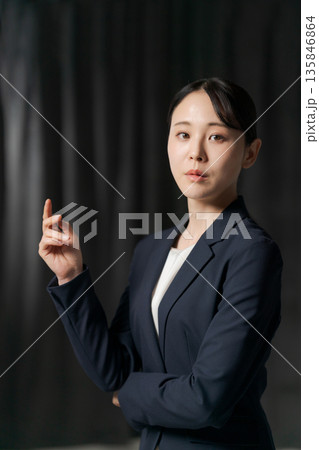 黒いカーテンの前にいるスーツの女性 黒いカーテンの前にいるスーツの女性 135846864