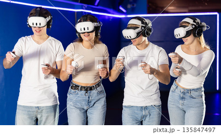 Friends playing video games in virtual reality headsets 135847497
