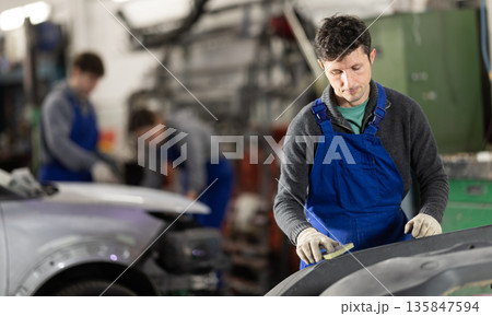 Man auto mechanic handle polishes body parts Man auto mechanic handle polishes body parts 135847594