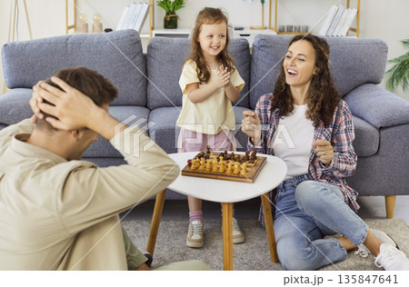 Happy family playing chess at home, mother celebrating victory, teaching child Happy family playing chess at home, mother celebrating victory, teaching child 135847641