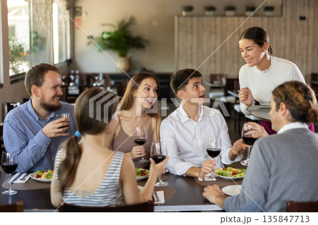 Female waitress taking order from group of friends in restaurant 135847713