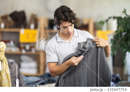 In chain shop, young man choose sweater 135847754