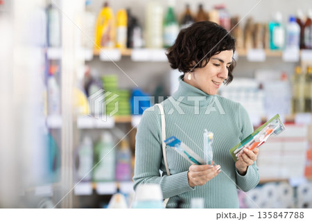 Middle-aged woman choosing toothbrush in retail store Middle-aged woman choosing toothbrush in retail store 135847788