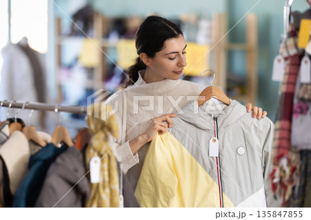 Young woman choosing down jacket in clothing store 135847855