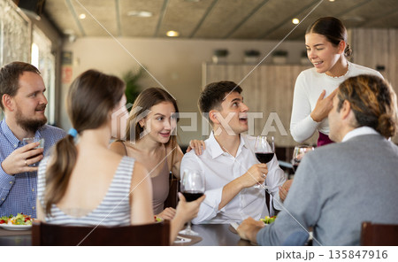 Female waitress taking order from group of friends in restaurant 135847916