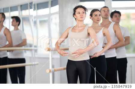 Group of dancers stand in first position at barre Group of dancers stand in first position at barre 135847919