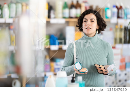 Middle-aged woman choosing cosmetics at supermarket Middle-aged woman choosing cosmetics at supermarket 135847920
