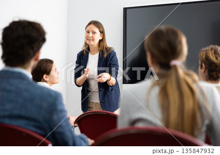 Competent female tutor teaching students in college classroom Competent female tutor teaching students in college classroom 135847932