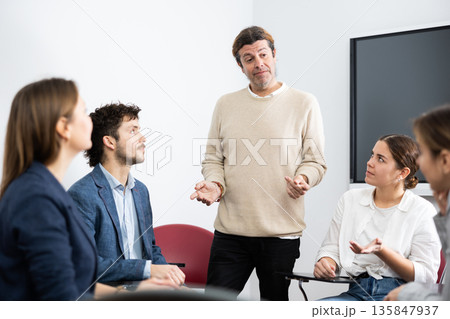 Experienced male teacher giving lecture to group of student 135847937