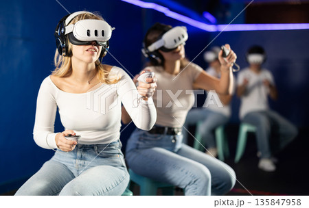 Two girls wearing virtual reality glasses participate in game with opponents 135847958