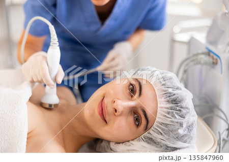 Young woman undergoing ultrasound cosmetic treatment on chest and neck area Young woman undergoing ultrasound cosmetic treatment on chest and neck area 135847960