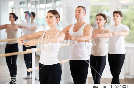 Group of dancers stand in fifth position at barre Group of dancers stand in fifth position at barre 135848013