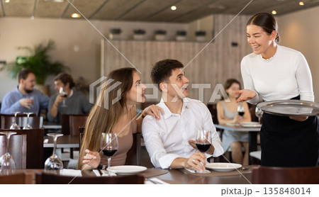 Positive waitress taking order from married couple in restaurant Positive waitress taking order from married couple in restaurant 135848014