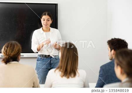 Young female professor explaining subject to classroom full of students 135848019