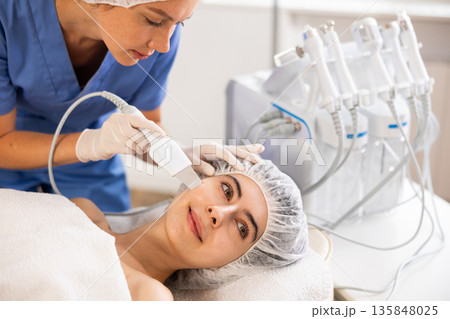 Young woman undergoing facial cleansing procedure using ultrasonic shovel 135848025