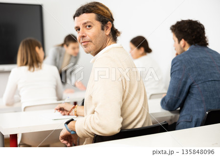 Positive middle-aged man turning around and looking at camera during advanced training course in auditory 135848096