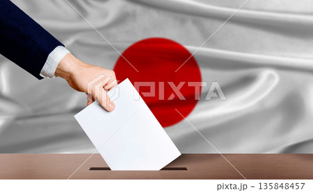 Japan presidential vote 2026. Hand placing a ballot in ballot box with the Japanese flag in the background 135848457