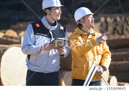 ノギスとタブレットを持って丸太を測る男性 135849645