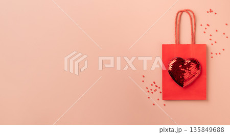 Red gift bag featuring sequin heart on pink background Red gift bag featuring sequin heart on pink background 135849688