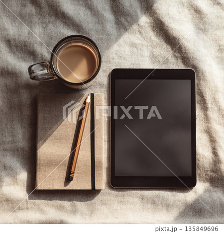 タブレットとノート、コーヒーのあるミニマルな作業デスクの俯瞰 タブレットとノート、コーヒーのあるミニマルな作業デスクの俯瞰 135849696