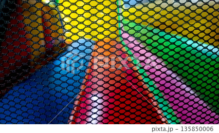 Close Up of Black Safety Net with Blurred Colorful Inflatable Playground Background 135850006