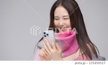 スマホを見るマフラーをした30代女性 135850527