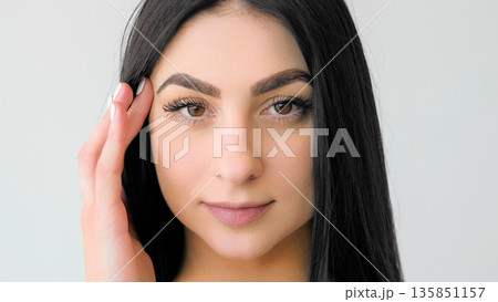 Treatment beauty. Perfect skin. Young female touching soft face. Girl with long hair demonstrating natural makeup isolated on white. Treatment beauty. Perfect skin. Young female touching soft face. Girl with long hair demonstrating natural makeup isolated on white. 135851157