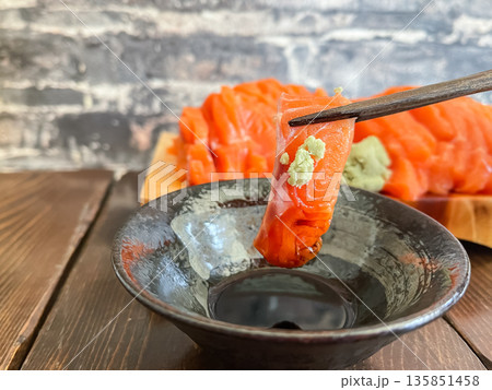 新鮮なサーモンの刺身のとわさび。箸持ちした刺身の断面。 135851458