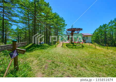 初夏の長野県東御市(群馬県嬬恋村)の湯の丸高原の道標と観光リフト山頂駅を見る 135851974
