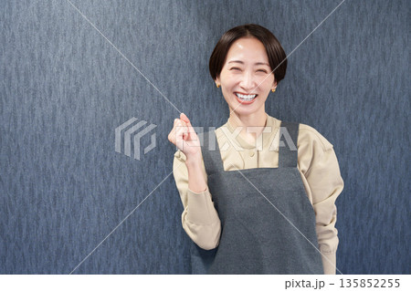 エプロンを着たガッツポーズをする女性店員 135852255