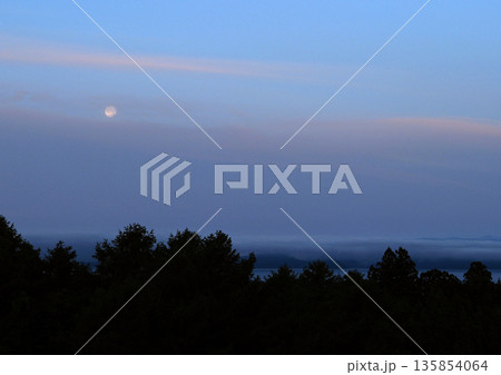 夜明け前、朝焼けの残るピンク色の雲と白く輝く月が印象的で綺麗だ。 夜明け前、朝焼けの残るピンク色の雲と白く輝く月が印象的で綺麗だ。 135854064