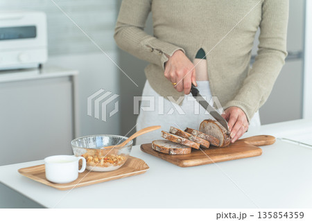 キッチンで朝食にパンをカットする女性の手元 キッチンで朝食にパンをカットする女性の手元 135854359