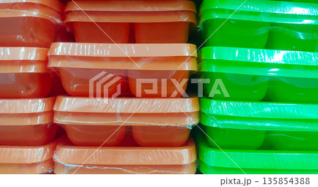 Vibrant Orange and Green Plastic Food Containers in Plastic Wrap Vibrant Orange and Green Plastic Food Containers in Plastic Wrap 135854388