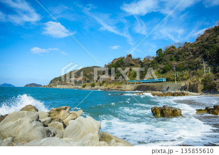 糸島の海岸線を走る青い電車と波しぶき 135855610