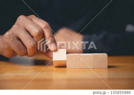 Sign of a new beginning as a closeup man hand pose and gesture places a wooden block, a blank sign for adding text or symbols to show a business concept or development Sign of a new beginning as a closeup man hand pose and gesture places a wooden block, a blank sign for adding text or symbols to show a business concept or development 135855980