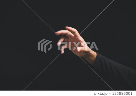 Closeup of a man hand in a dramatic pose, making a gesture or sign to reach for something on a dark background, a symbolic sign showing the concept of wanting something Closeup of a man hand in a dramatic pose, making a gesture or sign to reach for something on a dark background, a symbolic sign showing the concept of wanting something 135856001