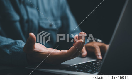 Close-up of hand on laptop keyboard, fingers typing, dark blue shirt in the background. Close-up of hand on laptop keyboard, fingers typing, dark blue shirt in the background. 135856016