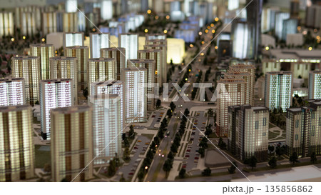 A detailed display shows a modern city layout with numerous buildings, streets, and green spaces. This real estate model highlights structures characteristic of the district. A detailed display shows a modern city layout with numerous buildings, streets, and green spaces. This real estate model highlights structures characteristic of the district. 135856862