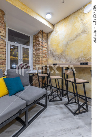 Modern hostel common area with bar seating and cozy sofa at night 135857866