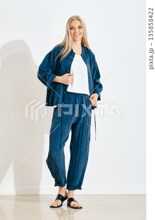 Woman posing in casual outfit with blue fabric in a bright indoor space Woman posing in casual outfit with blue fabric in a bright indoor space 135858422